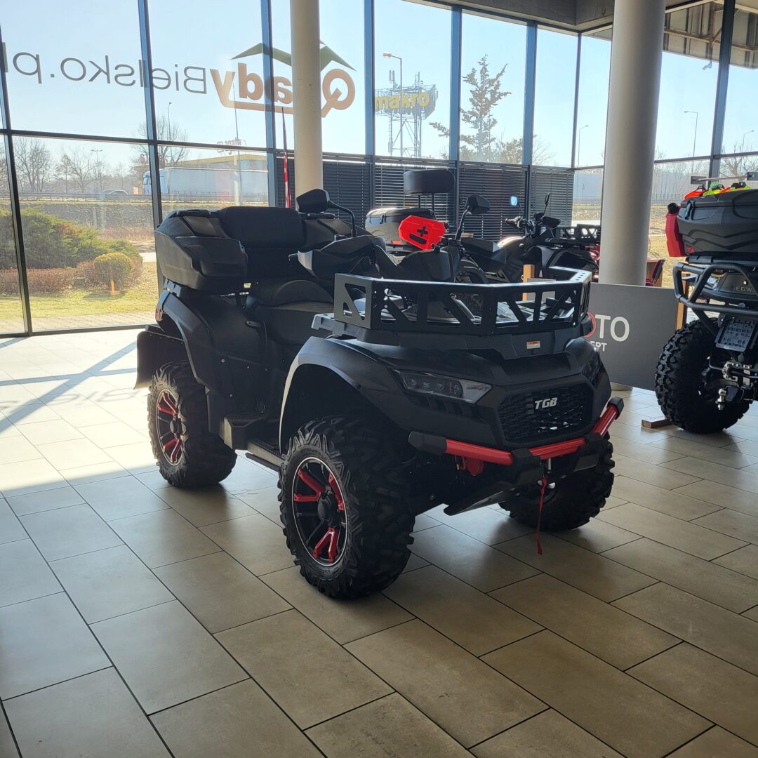 ATV TGB Blade 1000 LTX MAX: Czarny quad z czerwonymi akcentami w salonie.