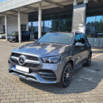 Nowy SUV Mercedes-Benz GLE580 4Matic 2022 w kolorze szarym parkowany przed salonem samochodowym.