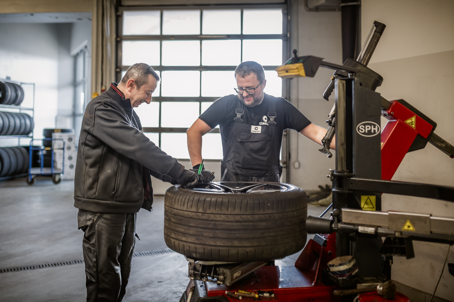 Dwóch mechaników pracuje wspólnie nad wymianą opon przy użyciu maszyny do montażu opon.