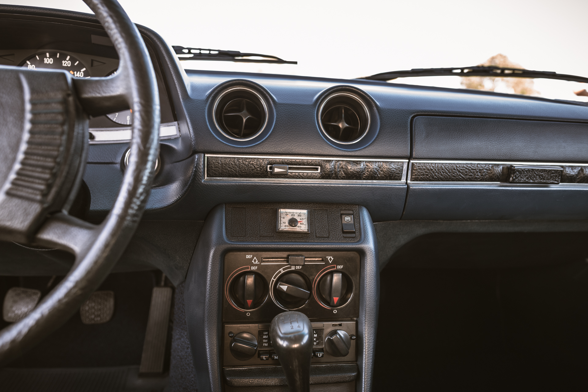 Wnętrze klasycznego Mercedesa-Benz W123: kierownica, deska rozdzielcza i panel sterowania.