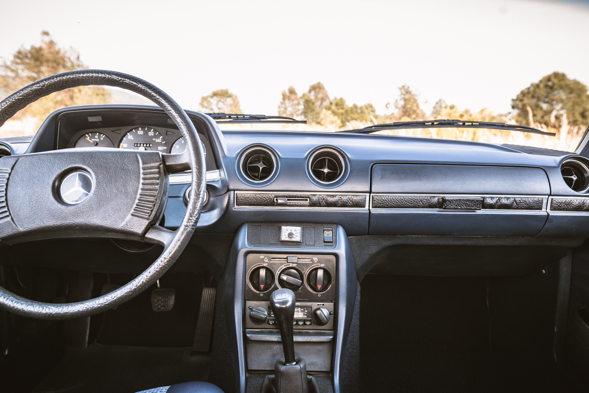Wnętrze klasycznego Mercedesa-Benz W123: deska rozdzielcza, kierownica i dźwignia zmiany biegów.