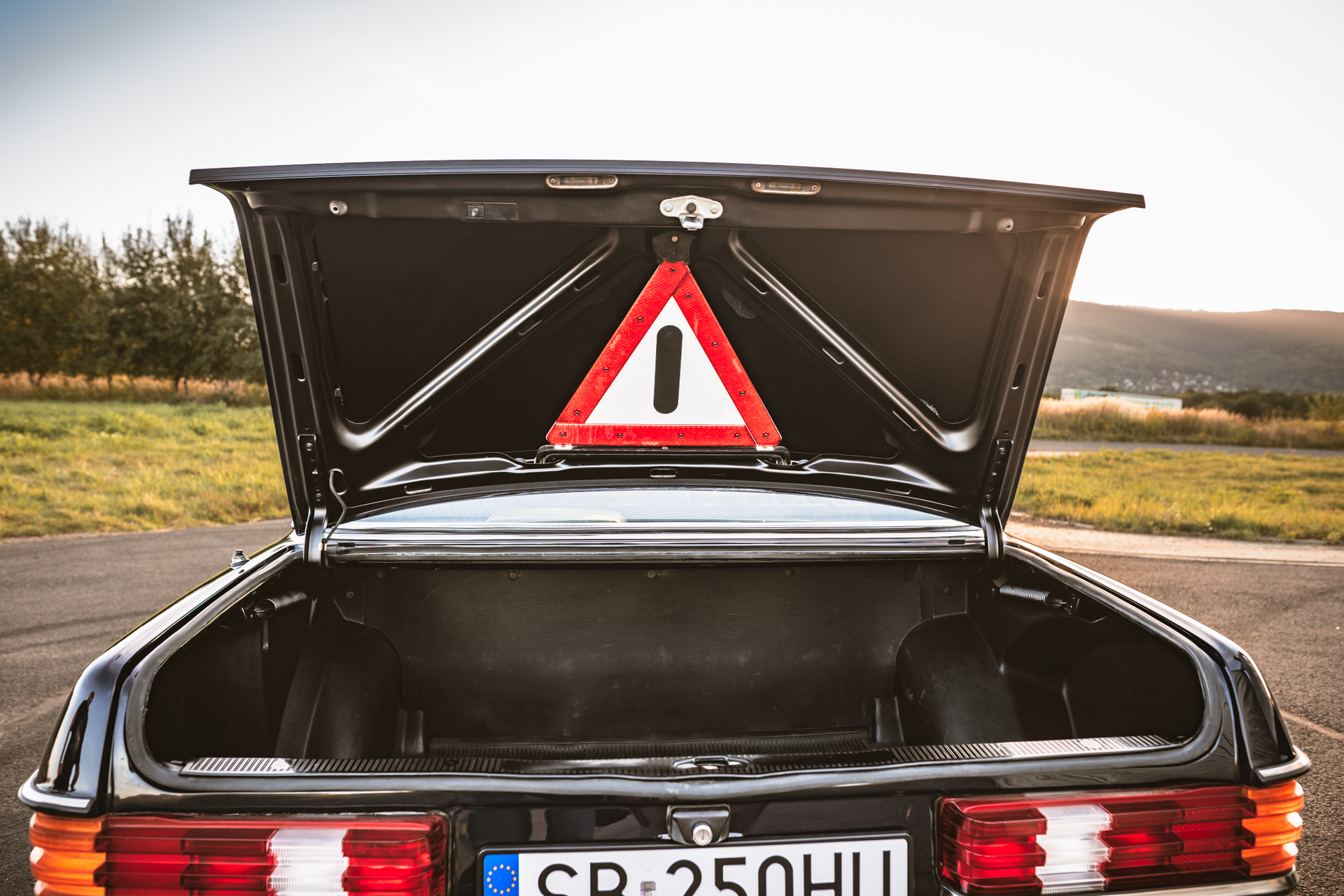 Otwarte tylne drzwi klasycznego Mercedesa W123 z trójkątem ostrzegawczym.