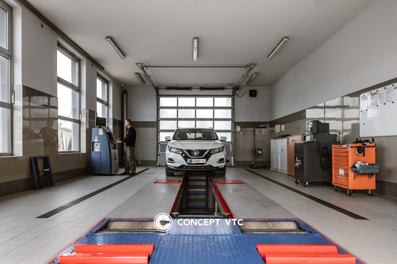 Technik obok kanału sprawdzający stan samochodu.