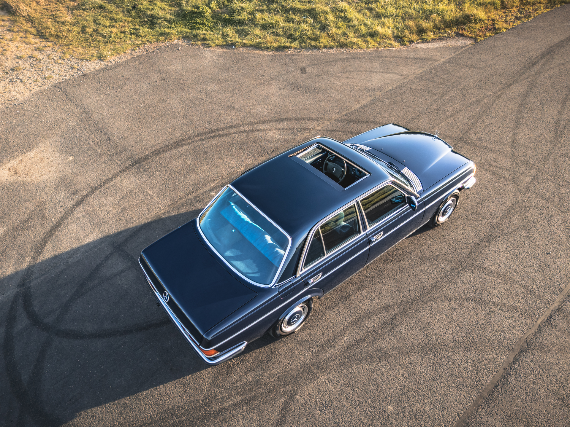 Ciemnoniebieski sedan Mercedes-Benz W123 z szyberdachem, widok z góry.