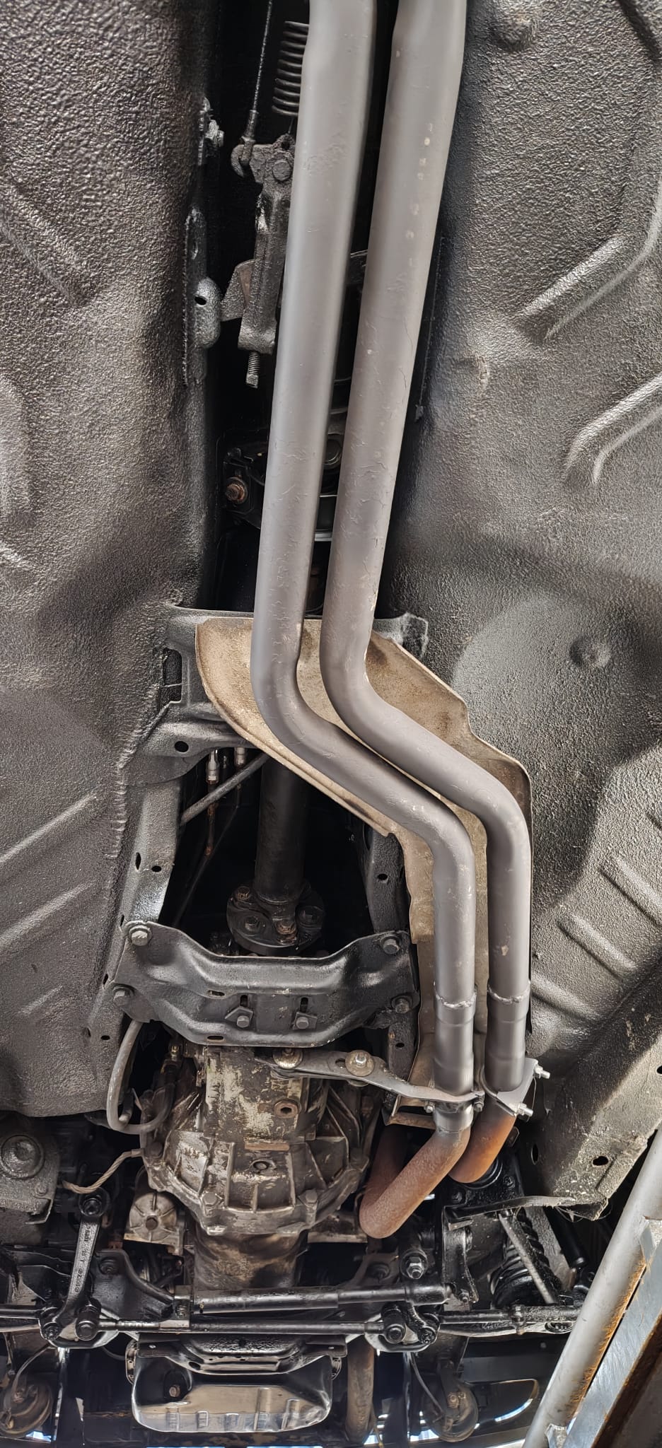 Spód Mercedes-Benz W123 z układem wydechowym i elementami napędu.