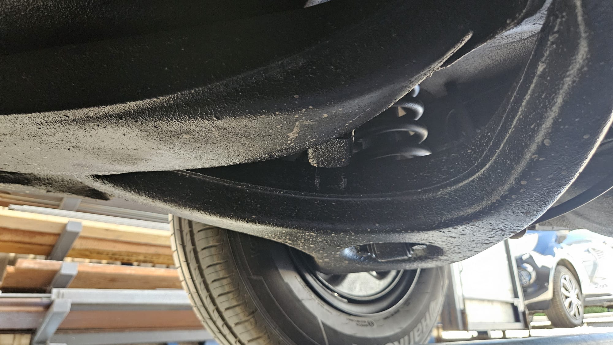 Podwozie Mercedes-Benz W123: widok od dołu na zawieszenie i oponę.